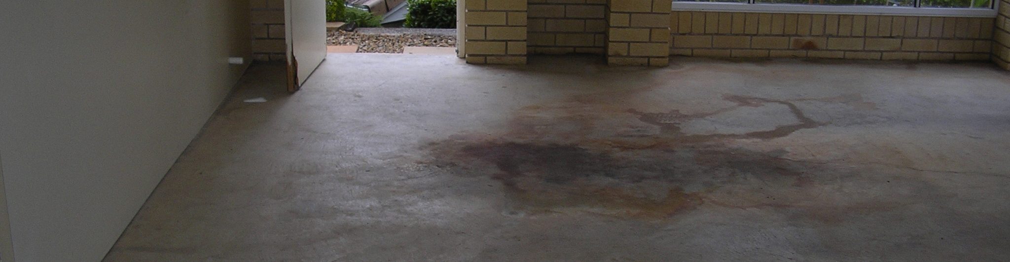 A garage floor with oil stains awaiting substrate assessment.