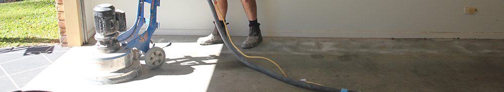 A grinder being used to mechanically prepare the surface in a residential garage.